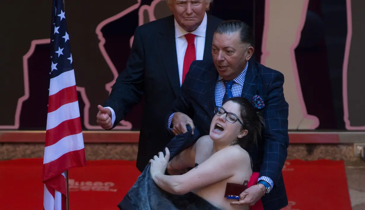 Petugas menangkap aktivis femen yang bertelanjang dada saat saat acara pembukaan patung lilin Presiden AS terpilih Donald Trump di Madrid's wax museum di Madrid, Spanyol, Selasa (17/1). (AP Photo/Paul White)