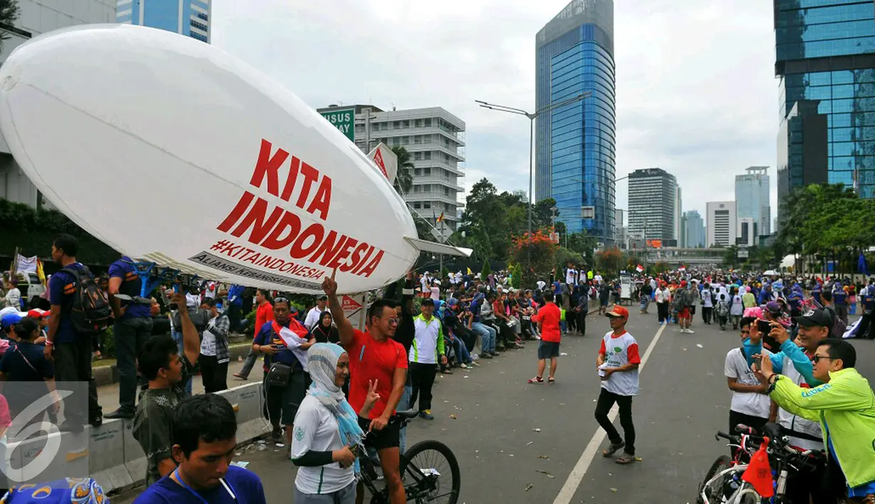 Sejumlah peserta berfoto di depan balon udara saat mengikuti aksi damai 'Kita Indonesia' di Bundaran HI, Jakarta, Minggu (4/12). Masayarakat yang memadati kawasan tersebut juga datang untuk mengikuti parade kebudayaan. (Liputan6.com/Angga Yuniar)