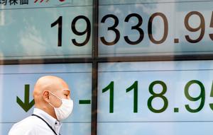 Seorang pria berjalan melewati indikator saham elektronik sebuah perusahaan sekuritas di Tokyo (29/8). Rudal tersebut menuju wilayah Tohoku dekat negara Jepang. (AP Photo/Shizuo Kambayashi)