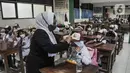 Guru membimbing murid kelas 1 saat Masa Pengenalan Lingkungan Sekolah (MPLS) di Sekolah Dasar (SD) Negeri Jati 06 Pagi, Pulogadung, Jakarta Timur, Senin (11/7/2022). PTM 100 persen tetap disiplin menerapkan protokol kesehatan guna mencegah penyebaran Covid-19 di lingkungan sekolah. (merdeka.com/Iqbal S. Nugroho)