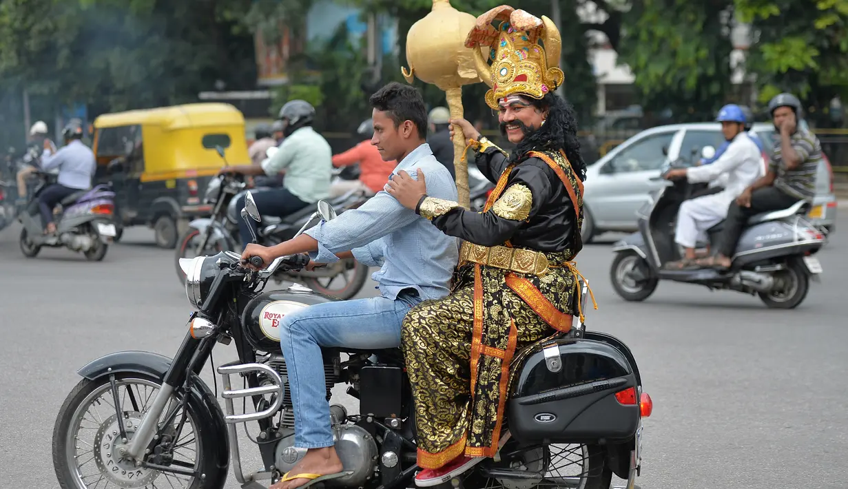 Pengendara motor tanpa helm membonceng seniman berpakaian seperti "Yamaraj" (R), dewa kematian Hindu saat  kampanye 'Road Safety Week' yang diselenggarakan oleh polisi lalu lintas di Bangalore (10/7). (AFP Photo/Manjunath Kiran)