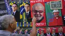 Seorang pria mengambil foto handuk bergambar Presiden Brasil Jair Bolsonaro (kiri) dan mantan Presiden Brasil Luiz Inacio da Silva atau Lula yang digantung untuk dijual menjelang pemilihan umum presiden di Rio de Janeiro, Brasil, 27 Juli 2022. Persilangan ideologi kedua kandidat mencerminkan perpecahan yang melanda Brasil. (AP Photo/Silvia Izquierdo)