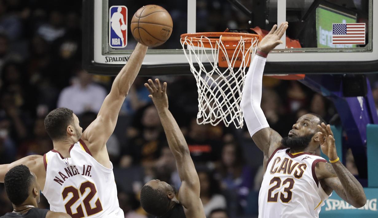 Pebasket Cleveland Cavaliers, LeBron James dan Larry Nance Jr, menghalau bola saat pertandingan melawan Charlotte Hornets pada laga NBA di Spectrum Center, Rabu (28/3/2018). Cleveland Cavaliers menang 118-105 atas Charlotte Hornets. (AP/Chuck Burton)