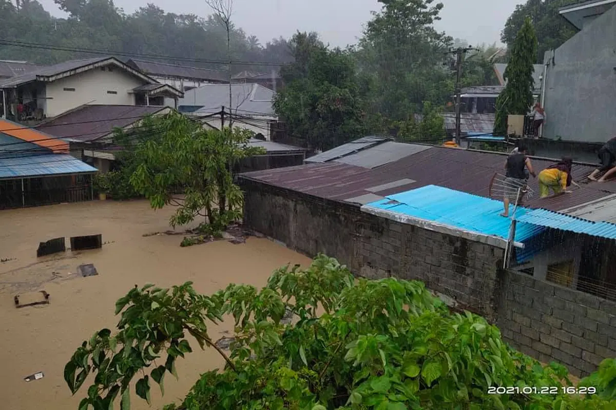 Sejumlah warga Manado memilih naik ke atap rumah karena volume air yang terus meningkat akibat banjir.