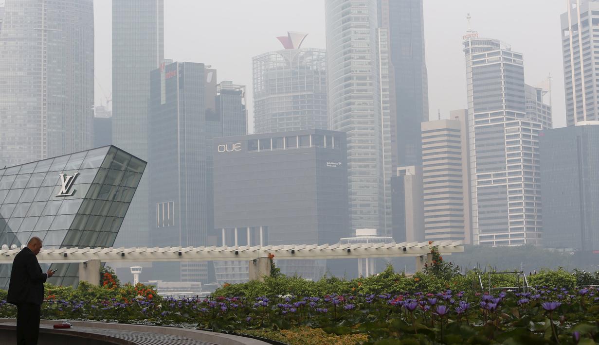 Seorang pria saat berada disamping skyline yang dikelilingi kabut tebal di Singapura (25/9/2015). Sejak Rabu Kualitas udara di Singapura mulai memburuk akibat kabut asap tebal dari wilayah Indonesia. (REUTERS/Edgar Su)