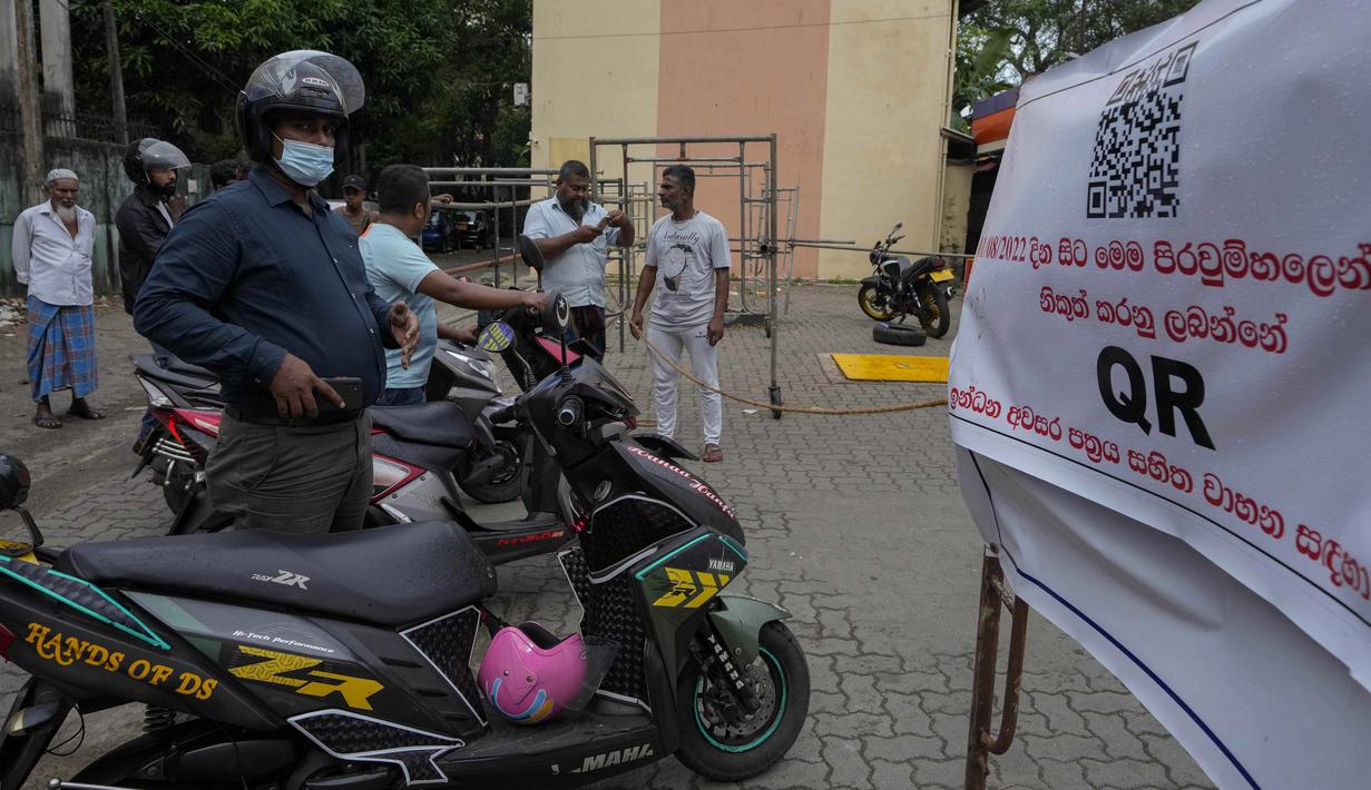 Pengemudi menunggu di sebelah spanduk yang bertuliskan hanya kendaraan dengan kode QR yang akan diberikan bahan bakar di SPBU di Kolombo, Sri Lanka, Senin, 1 Agustus 2022. Sri Lanka memperkenalkan distribusi bahan bakar menggunakan kode QR pada hari Senin sebagai bagian dari penerapan kuota mingguan untuk pengendara. (AP Photo/Eranga Jayawardena)