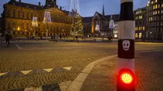 Gambar tengkorak direkatkan ke lampu lalu lintas di Dam Square yang hampir kosong dengan latar belakang Istana Kerajaan di Amsterdam, Selasa (15/12/2020). Pemerintah Belanda melakukan lockdown paling ketat selama lima pekan mulai dari Selasa (15/12) hingga 19 Januari 2021. (AP Photo/Peter Dejong)