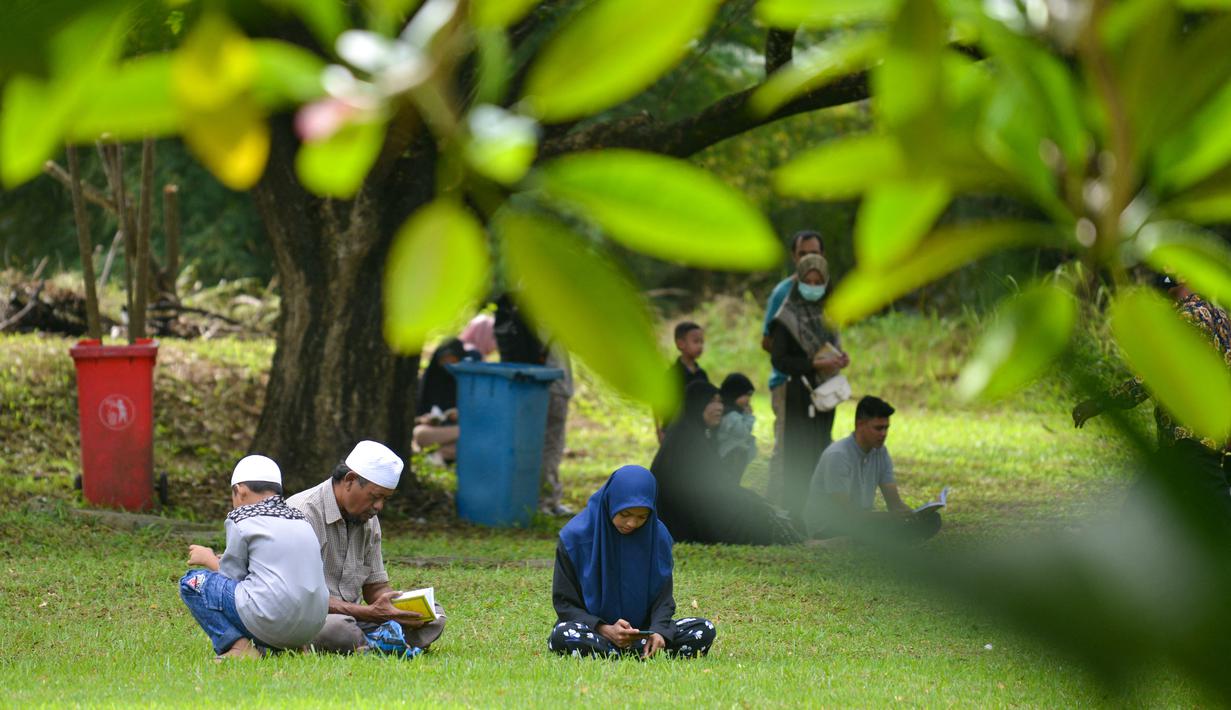 Orang-orang berdoa saat memperingati 18 tahun musibah gempa dan tsunami di kuburan massal Siron, Aceh, Senin (26/12/2022). Tsunami Aceh pada 2004 merenggut nyawa lebih dari 170.000 orang di Indonesia saja. (AFP/Chaideer Mahyuddin)