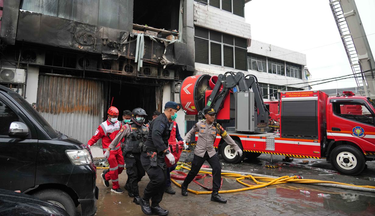 Api dengan cepat menyebar ke lantai 2, 3 hingga 6 dan asap pekat naik dengan cepat memenuhi tiap lantai di Gedung Terra Drone. Tampak dalam foto, personel dari Dinas Penanggulangan Kebakaran dan Penyelamatan mengevakuasi jenazah korban kebakaran di Jakarta, Selasa 9 Desember 2025. (AP Photo/Dita Alangkara)