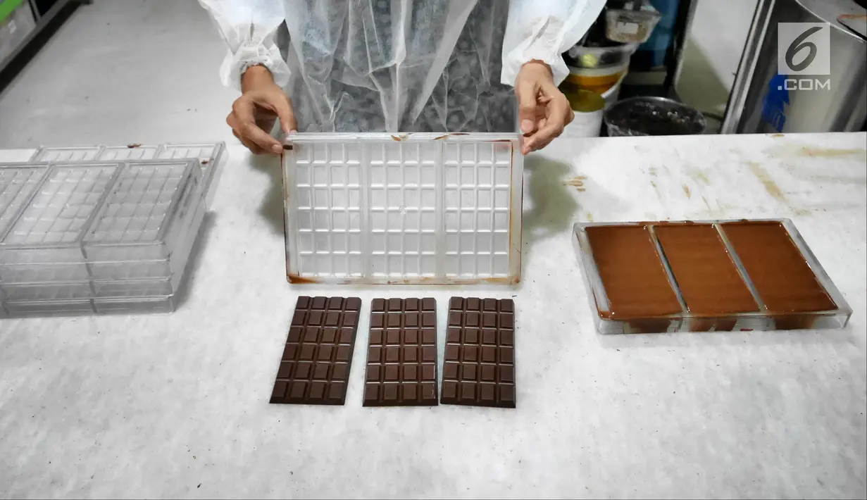 Pekerja mengeluarkan cokelat dari cetakan di toko Pipiltin Cocoa kawasan Barito, Jakarta, Kamis (13/9). Pipiltin Cocoa memiliki beragam rasa, varian, dan ukuran. (Liputan6.com/Herman Zakharia)