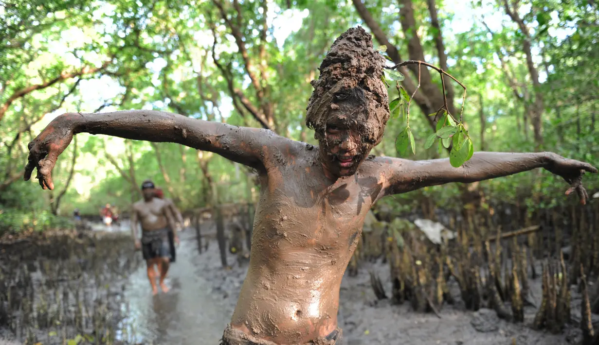 Seorang remaja berpose dengan badan penuh lumpur saat mengikuti Mebuug-buugan di desa Kedonganan, Bali (18/3). Mebuug-buugan ini diadakan sehari setelah Nyepi, bertujuan untuk menetralisir sifat-sifat buruk. (AFP/Sony Tumbelaka)