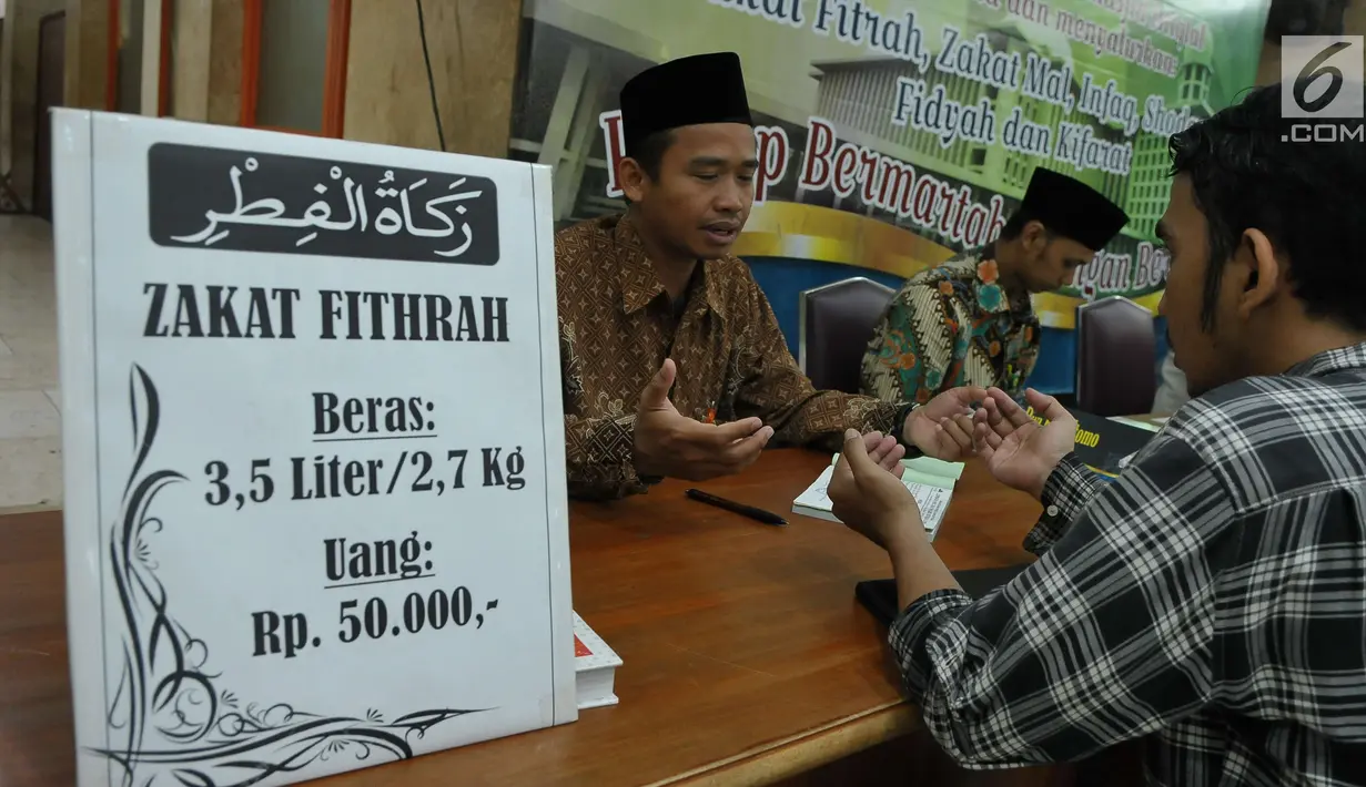 Petugas bersama seorang pria berdoa usai membayarkan zakat fitrah di Masjid Istiqlal, Jakarta, Jumat (23/6). Waktu pembayaran dibuka hingga malam takbiran dengan pembayaran zakat senilai Rp50ribu dan beras 3,5 liter. (Liputan6.com/Helmi Afandi)