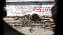 Tulisan cat merah dengan pesan Kami Rindu Rumah Kami dan tagar Pray for Palu menghiasi dinding rumah pasca gempa bumi dan tsunami di Jalan Trans Sulawesi, Palu, Sulawesi Tengah, Kamis (4/10). (Liputan6.com/Fery Pradolo)