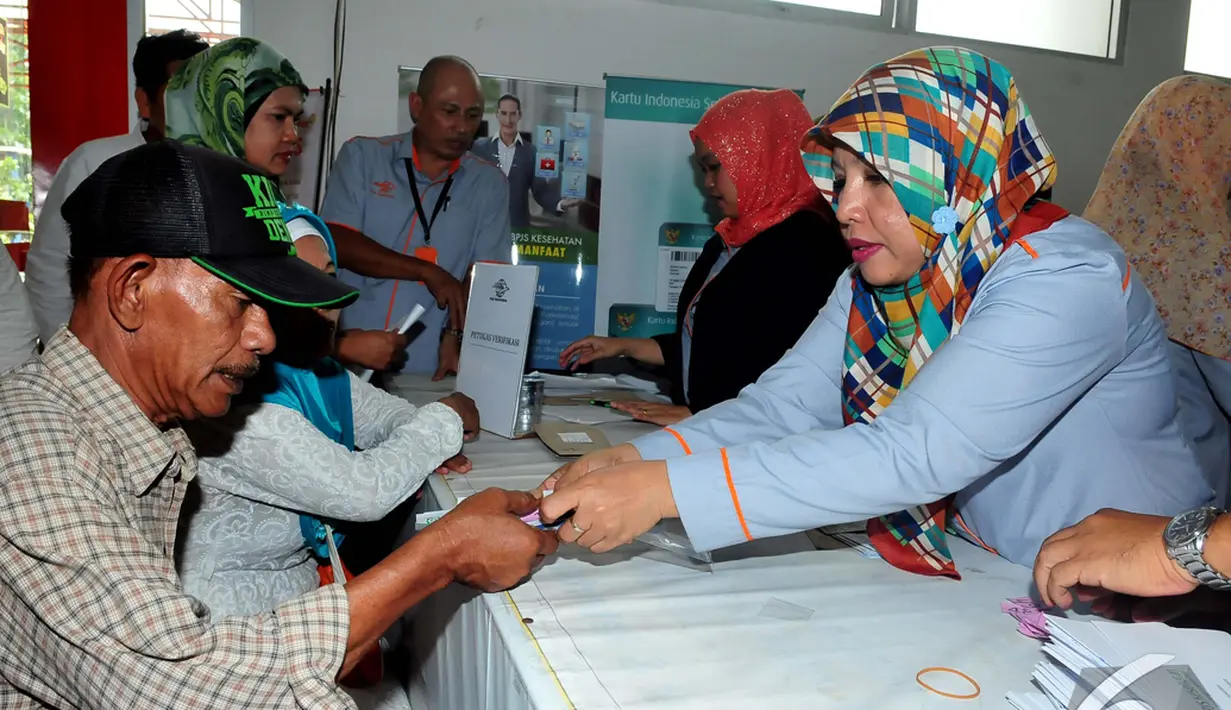 Seorang petugas memberikan warga Kartu Indonesia Sehat saat peluncuran perdana di Kantor Pos Fatmawati, Jakarta, Senin (3/11/2014). (Liputan6.com/Johan Tallo)