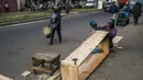 Mr. Jean dan timnya membuat peti mati murah di jalan, padahal kegiatan ini dilarang di jalan raya umum, di Antananarivo, Madagaskar, Rabu (14/4/2021). Peti mati dari kayu pinus yang diproduksi selama satu jam tersebut dijual antara Rp 350ribu hingga Rp 820ribu. (RIJASOLO/AFP)