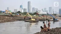 Anak-anak bermain dekat alat berat yang tengah mengerjakan pengerukan lumpur di Kali Ciliwung Segmen Kanal Banjir Barat (KBB), Tanah Abang, Kamis (30/9/2021). Gerebek Lumpur dilakukan secara serentak di lima wilayah Ibu Kota. (merdeka.com/Iqbal S. Nugroho)