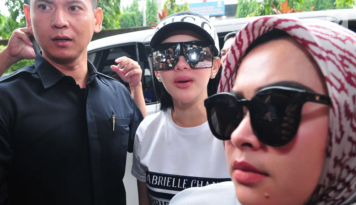 Penyanyi Syahrini (tengah) berjalan menuju ruang pemeriksaan di  Bareskrim Mabes Polri, Jakarta, Rabu (27/9). Pelantun lagu "Sesuatu" itu diperiksa sebagai saksi lantaran pernah mempromosikan First Travel. (Liputan6.com/Helmi Afandi)