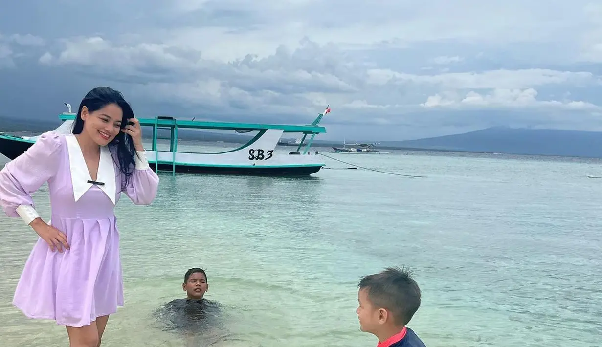 Bermain di pantai Banyuwangi, Titi tampak manis dengan long sleeve dress warna lilac dengan collar panjang. [Foto: IG/titi_kamall].