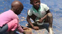 Anak-anak mengumpulkan biji gandum yang tercecer saat distribusi bantuan makanan di Chiredzi Mupinga, Zimbabwe, Selasa (6/10). Puluhan juta orang di sub-Sahara Afrika terancam kelaparan akibat siklus El Nino mencapai puncaknya.(REUTERS/Philimon Bulawayo)