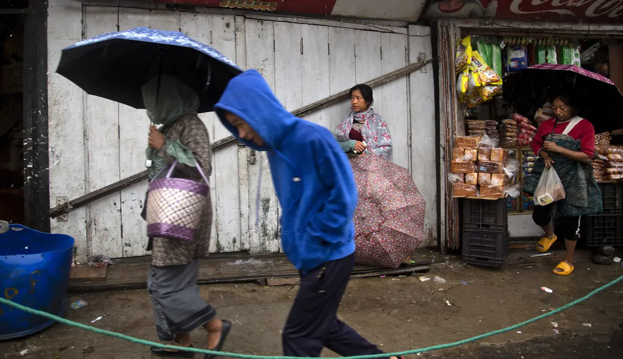 Orang-orang berjalan saat hujan di Kohima, Nagaland, India, Senin (16/5/2022). Delapan orang tewas akibat banjir dan tanah longsor yang dipicu oleh hujan lebat di wilayah timur laut India. (AP Photo/Yirmiyan Arthur)