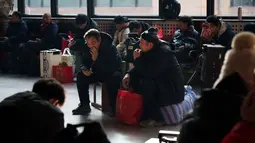 Gelombang mudik tahunan terbesar di dunia ini resmi dimulai sejak Senin (2/2/2026) atau tepat 15 hari menjelang perayaan Tahun Baru Imlek atau Festival Musim Semi 2026. Tampak dalam foto, para penumpang duduk di samping barang bawaan mereka sambil menunggu di stasiun kereta api dalam perjalanan pulang selama liburan Tahun Baru Imlek di Beijing, China, Selasa 10 Februari 2026. (AP Photo/Vincent Thian)