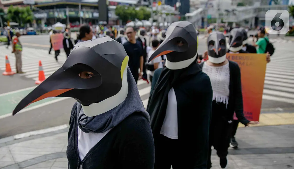 Sejumlah aktivis Greenpeace mengenakan topeng penguin saat menggelar aksi dalam car free day di kawasan Thamrin, Jakarta, Minggu (9/2/2020). Mereka mengajak pemerintah untuk berpartisipasi dalam mewujudkan Perjanjian Laut Internasional (Global Ocean Treaty). (Liputan6.com/Faizal Fanani)