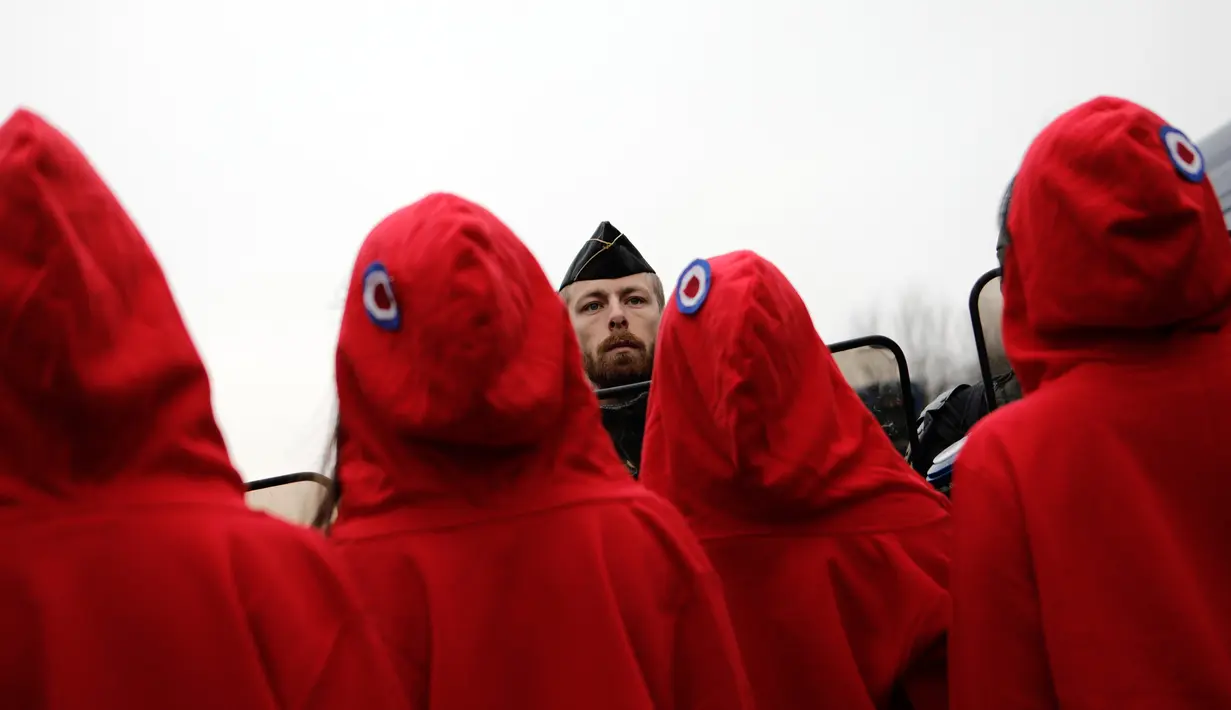 Polisi antihuru-hara menghadang aktivis wanita bertelanjang dada saat aksi protes rompi kuning di Paris, Prancis, Sabtu (15/12). Pengunjuk rasa memperluas tajuk demo mereka pada ketidakpuasan terkait kebijakan ekonomi presiden. (AP Photo/Kamil Zihnioglu)