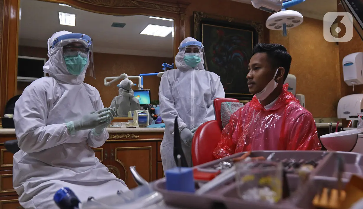 drg. Ayusha (kiri) mengenakan alat perlindungan diri (APD) saat memeriksa pasien di salah satu klinik di kawasan Pulo Gadung, Jakarta, Rabu (22/4/2020). Penggunaan APD dilakukan sebagai SOP pemeriksaan gigi saat pandemi serta mengantisipasi penularan COVID-19. (Liputan6.com/Herman Zakharia)