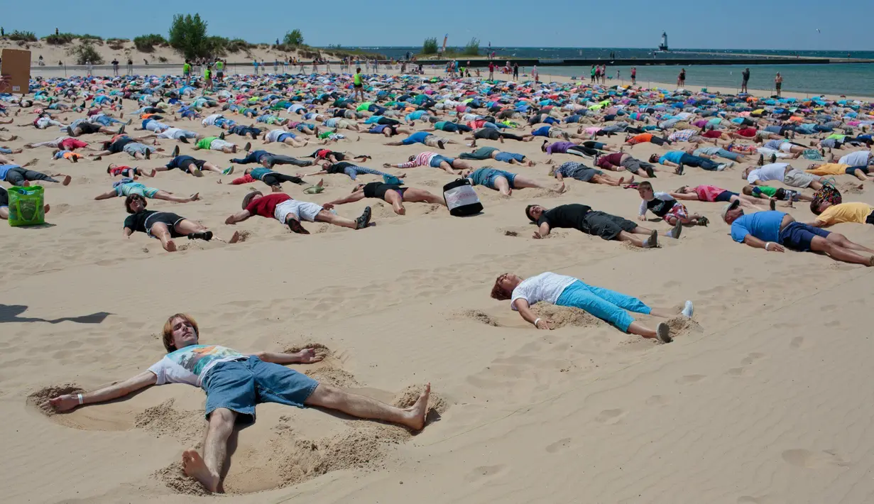 Peserta mengepakan tangannya untuk membuat "Sand Angels" atau Malaikat Pasir di Pantai Stearns Park, Ludington (10/6). Mereka berhasil memecahkan rekor Malaikat Pasir terbanyak di dunia dengan 1.387 orang. (Joel Bissell / Muskegon Chronicle via AP)
