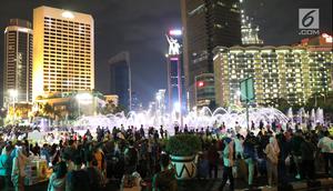 Warga menikmati car free night saat malam pergantian tahun di kawasan Bundaran HI, Jakarta, Senin (31/12). Hujan yang mengguyur Jakarta sejak siang tidak menyurutkan antusias warga menikmati&nbsp;car free night. (Liputan6.com/Angga Yuniar)