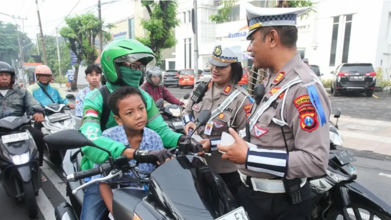 Dua Polantas mengingatkan pengendara motor agar penumpangnya mengenakan helm saat Operasi Zebra Semeru di Surabaya, Jawa Timur.