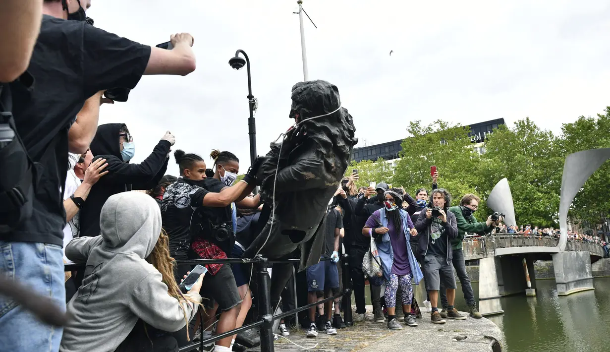 Demonstran melempar patung pedagang budak Edward Colston ke Pelabuhan Bristol saat protes Black Lives Matter di Bristol, Inggris, Minggu (7/6/2020). Aksi tersebut dilakukan sebagai bentuk protes atas kematian George Floyd saat ditangkap oleh polisi di Amerika Serikat. (Ben Birchall/PA via AP)