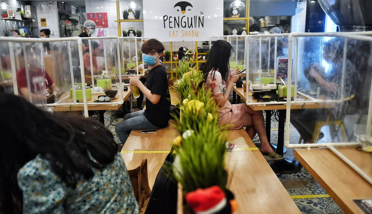 Pengunjung makan di sela-sela pembatas plastik untuk mencegah penyebaran virus corona di restoran hotpot Penguin Eat Shabu di Bangkok, 5 Mei 2020. Restoran kembali dibuka setelah Thailand memperlonggar lockdown dengan mengizinkan tempat makan menerapkan social distancing. (Lillian SUWANRUMPHA/AFP)