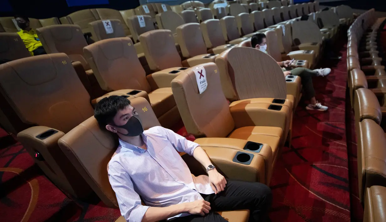 Pengunjung memakai masker duduk menjauh untuk mencegah penyebaran Covid-19 ketika mereka menonton film di bioskop Paragon Cineplex di Bangkok, Thailand, Senin (1/6/2020). (AP Photo/Sakchai Lalit)