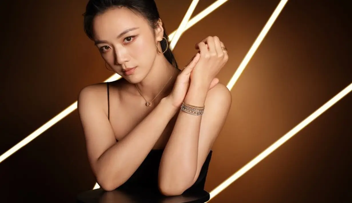 Di dalam permukaan mikro ini, cahaya menemukan banyak titik refraksi, yang memperkuat kilauan perhiasan seperti perhiasaan yang dikenakan Tang Wei. Ia mengenakan kalung berliontin dan anting-anting hoop. [Chopard]