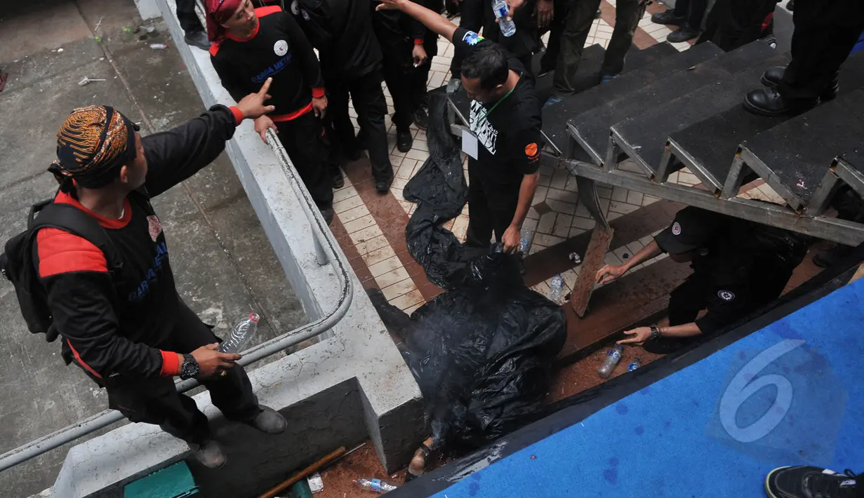 Sejumlah petugas mengevakuasi jenazah pria yang terjun dengan membakar diri dari atap stadion Gelora Bung Karno, Jakarta, Jumat (1/5/2015). Polisi masih mencari motif dari kejadian tersebut. (Liputan6.com/Herman Zakharia)