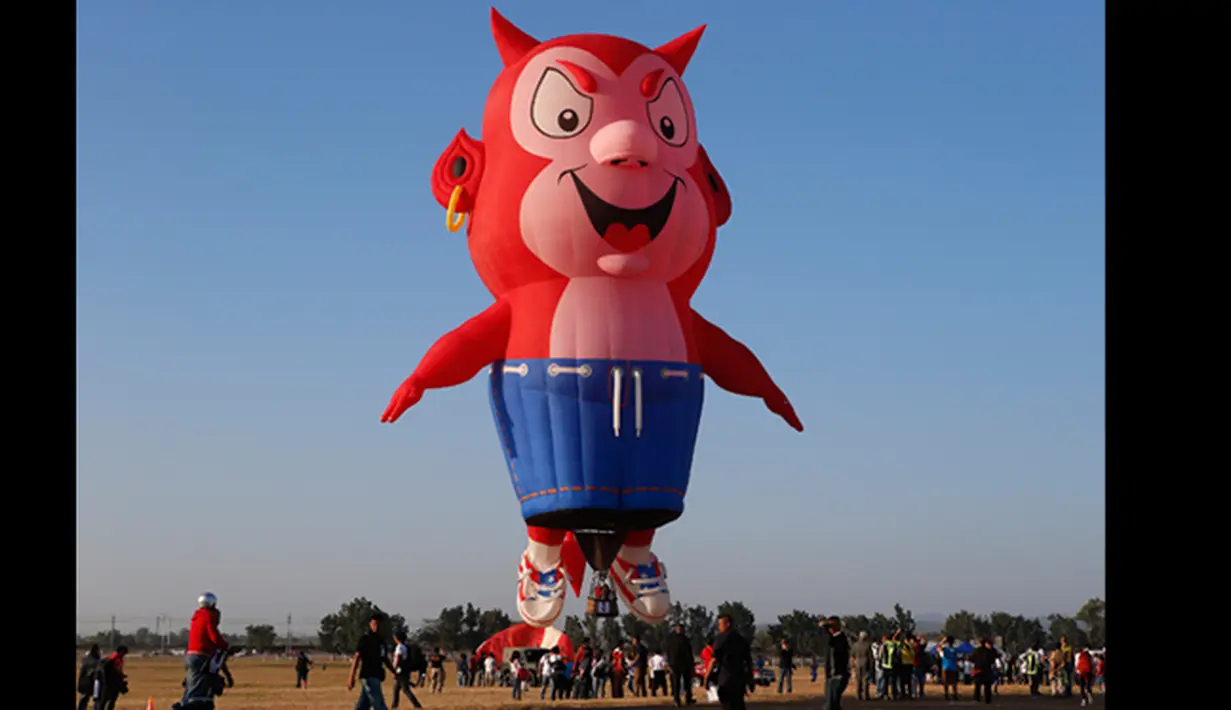 Penonton mengambil gambar dan menonton Burnie balon udara Little Devil saat lepas landas selama Filipina International Hot Air Balloon Fiesta, Manila, Kamis (12/2/2015). (Reuters / Erik De Castro)