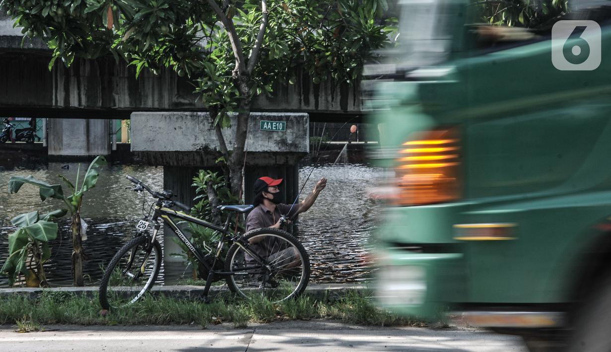 Kendaraan melintas di dekat warga yang sedang memancing di Kali Ancol, Jakarta Utara, Kamis (11/3/2021). Ikan yang biasa didapat warga antara lain bawal dan mujair. (merdeka.com/Iqbal S. Nugroho)