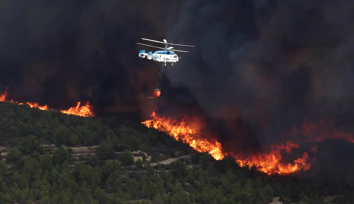 Sebuah helikopter membawa air untuk memadamkan kebakaran hutan di Benitatxell dekat Alicante, Spanyol, Senin (5/9). Sedikitnya 1.000 orang terpaksa diungsikan ke tempat yang lebih aman dari sejumlah vila. (REUTERS / Heino Kalis)