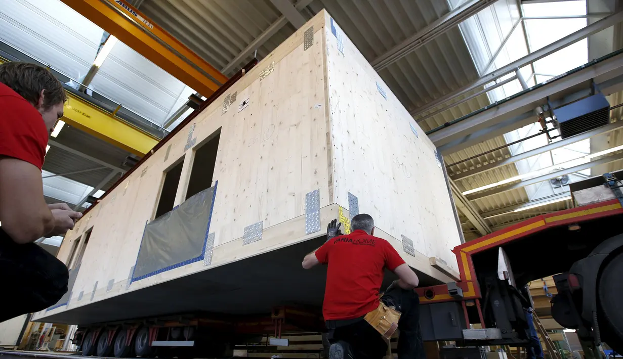 Pegawai bangunan saat merekonstruksi sebuah rumah prefabrikasi untuk pengungsi di perusahaan konstruksi Bauer Holzsysteme, Jerman, (7/12).  Rumah prefabrikasi ini dapat diangkut dan dipindahkan dengan menggunakan truk angkut. (REUTERS/Michaela Rehle)