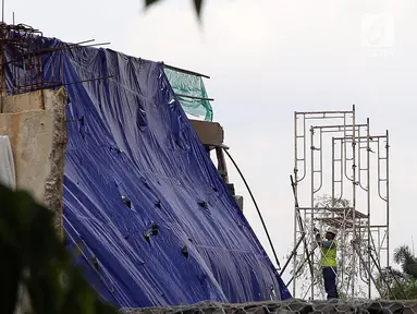 Petugas melihat sisa robohnya bangunan proyek Apartemen Pakubuwono Spring 3 yang ditutupi terpal di Jalan Teuku Cut Nyak Arief, Jakarta, Rabu (27/12). Akibat insiden ini, tiga orang tewas. (Liputan6.com/JohanTallo)