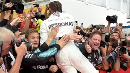 Pembalap Mercedes, Lewis Hamilton berselebrasi dengan timnya setelah menjuarai balapan F1 GP Jerman di Sirkuit Hockenheim, Minggu (22/7). Kemenangan ini diraih secara dramatis karena Hamilton mengawali balapan dari urutan ke-14. (AP/Jens Meyer)