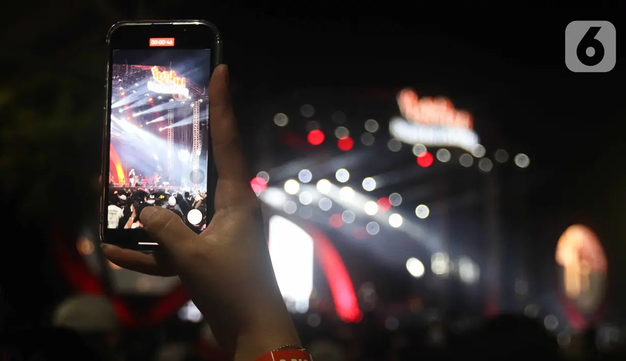 Pengunjung mengabadikan dengan ponselnya konser musik pada acara "Pestapora 2022" di Gambir Expo Kemayoran, Jakarta, Sabtu (24/9/2022). Pada acara pertunjukan musik Indonesia yang berlangsung 23-25 September 2022 tersebut menghadirkan enam panggung pertunjukan dengan menampilkan berbagai musisi tanah air.  (Liputan6.com/Herman Zakharia)