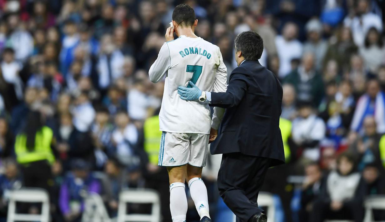 Striker Real Madrid, Cristiano Ronaldo, keluar lapangan saat mengalami pendarahan di bagian pelipis pada laga La Liga di Stadion Santiago Bernabeu, Minggu (21/1/2018). Real Madrid menang 7-1 atas Deportivo La Coruna. (AFP/Oscar Del Pozo)
