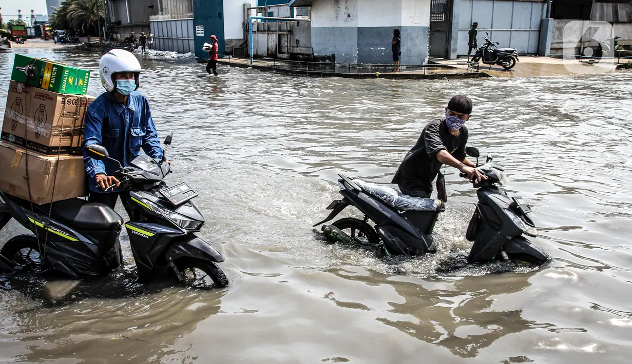 Kendaraan bermotor melintasi jalan yang tergenang air rob (banjir pasang air laut) di Kawasan Pasar Ikan Muara Baru, Jakarta, Kamis (4/6/2020). Banjir rob di Pelabuhan Muara Baru tersebut terjadi akibat cuaca ekstrem serta pasangnya air laut. (Liputan6.com/Faizal Fanani)