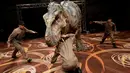 Robot dinosaurus "mengigit" seorang mekanik robot TRX03 di aula pertemuan sebuah hotel di Tokyo, Jepang, Kamis (10/11). Robot ini didesain mirip seperti aslinya, mulai kontur kulit, gerak jalan, hingga amukan hewan purba tersebut. (REUTERS/Toru Hanai)