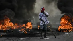 Demonstran berdiri dekat kobaran api saat menuntut keadilan atas pembunuhan Presiden Haiti Jovenel Moise di Cap-Haitien, Haiti, Kamis (22/7/2021). Demonstrasi menuntut keadilan atas pembunuhan Presiden Haiti Jovenel Moise terus berlanjut dan menimbulkan kerusuhan. (AP Photo/Matias Delacroix)