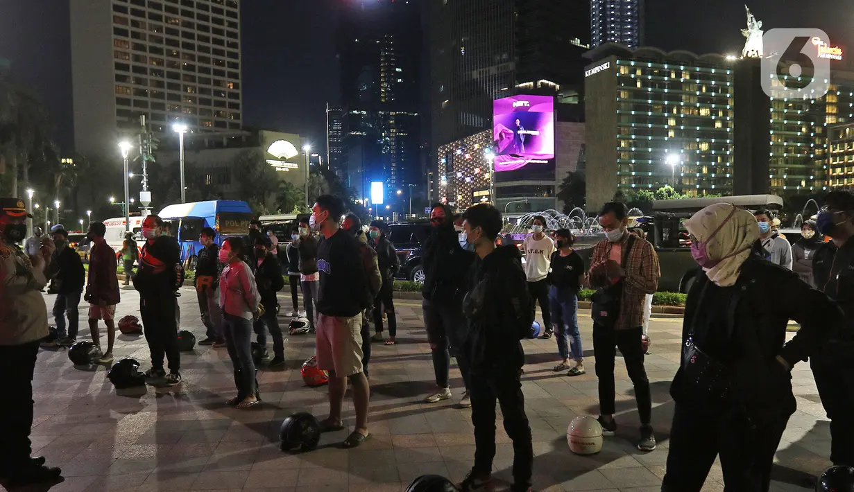Sejumlah orang yang terjaring saat patroli penegakan protokol kesehatan COVID-19 di bawa ke pos polisi bundaran HI, Jakarta Pusat, Sabtu (26/12/2020). Dalam kegiatan itu, aparat mengamankan sejumlah pemuda untuk dilakukan Rapid Test smassal dan diberi sanski menyapu. (Liputan6.com/Herman Zakharia)