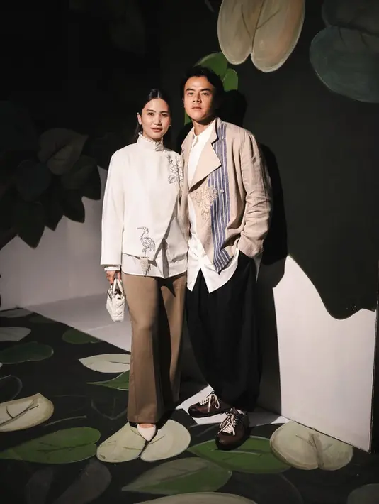 Dion Wiyoko tampil serasi dengan sang istri Fiona di show BIYAN Spring Summer 2027. Dion Wiyoko padukan kemeja putih dengan outer linen, sedangkan Fiona tampil effortless dengan beskap putih bermotif bunga dan flamingo [@biyanofficial]
