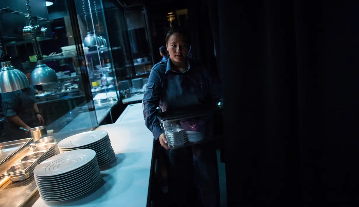 Seorang wanita bekerja di dapur untuk menyiapkan hidangan bagi tamu Restoran Ultraviolet di Shanghai, 11 Oktober 2017. Setiap pengunjung harus mengisi daftar antrean yang sudah tersedia di laman Restoran Ultraviolet. (CHANDAN KHANNA / AFP)